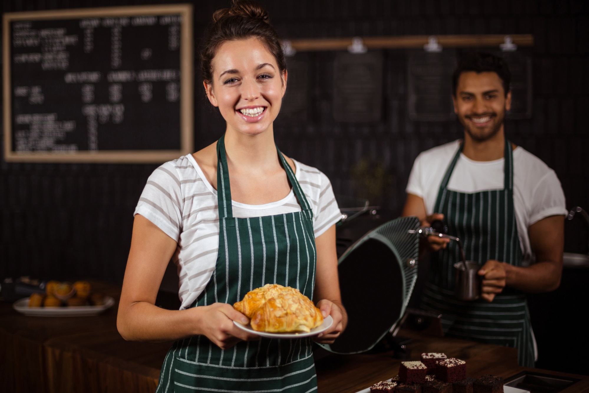 Smiling barista holding croissants - Amount of the minimum wage in 2023